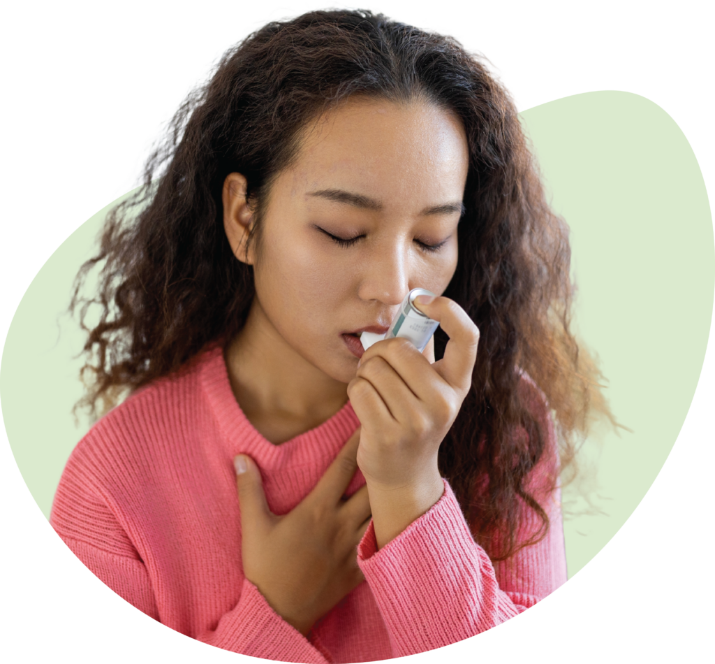 A woman using an inhaler clutching her chest.